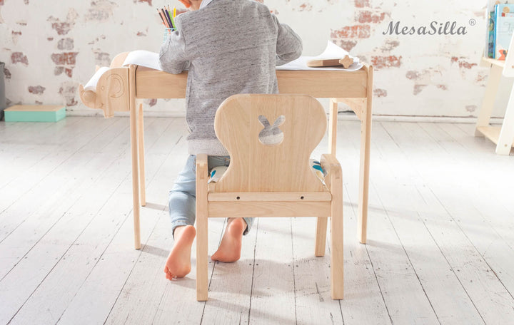 a little girl sitting at a desk with a book