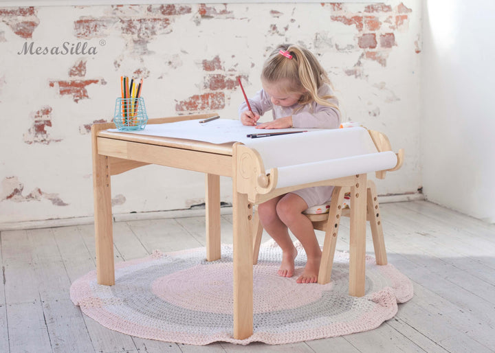 a little girl sitting at a desk writing on a piece of paper