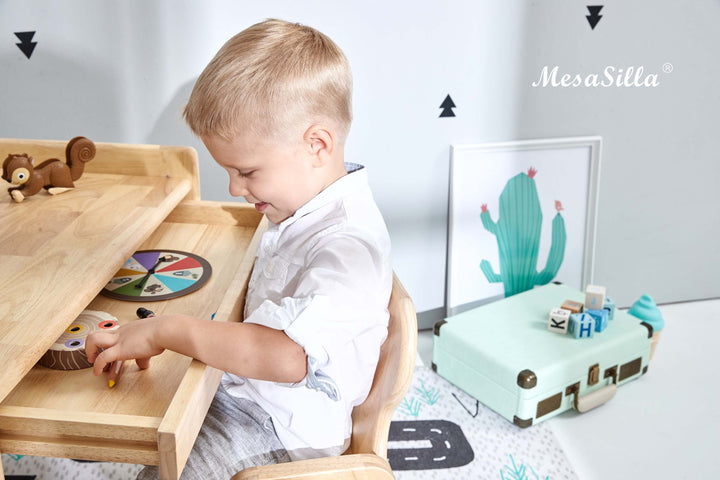 a little boy sitting at a table with a toy